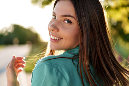 Portrait of young woman in green shirt smiling in a park