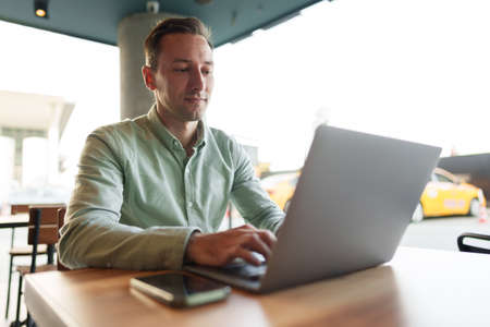 Young businessman sitting in cafe working with laptop computerの写真素材