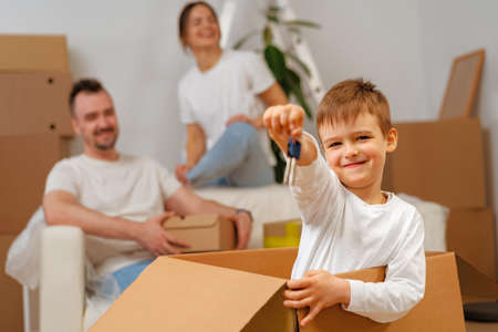 Portrait of happy family with cardboard boxes in new house at moving day