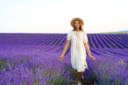 Young woman in a white dress walking in a lavender fieldの写真素材
