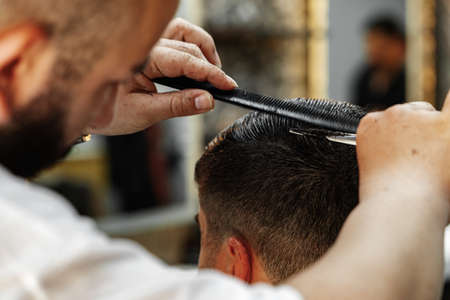 Male client getting haircut by hairdresser in barbershopの写真素材