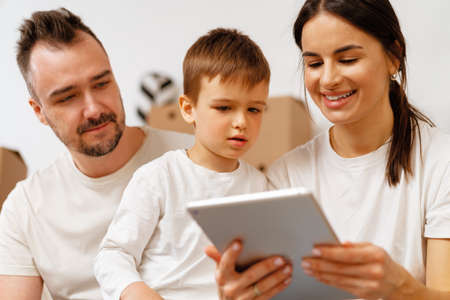 Portrait of happy family with cardboard boxes in new house at moving dayの写真素材