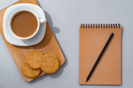 Cup of coffee with notebook on gray background top viewの写真素材