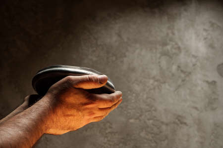 Male hands holding empty plate on dark background, lack of food, hunger concept.の写真素材