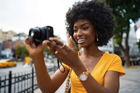 Smiling African american woman using professional camera at a streetの写真素材