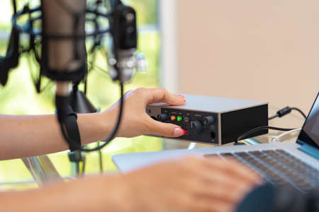 Unrecognizable young woman hands adjusting audio mixer setting sound in home studio close upの写真素材
