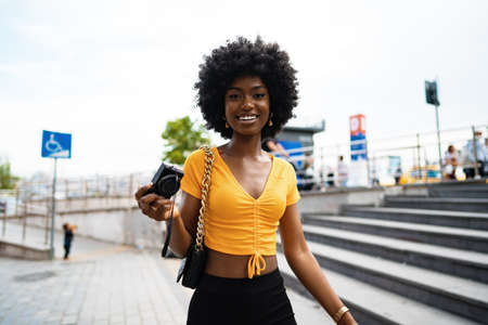 Smiling African american woman using professional camera at a street