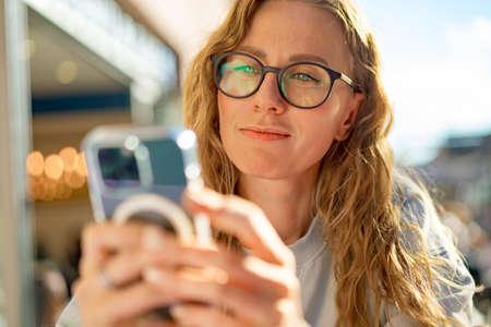 Young woman in a cafe reading a text message from her mobile phoneの写真素材