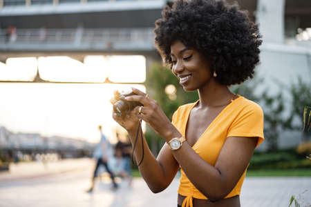 Smiling African american woman using professional camera at a street