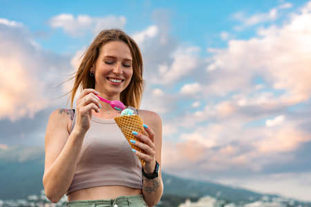 Young woman with ice cream walking in the street