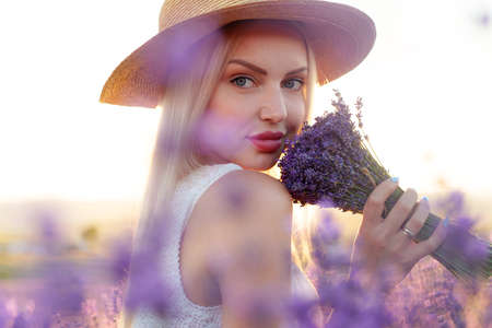 Portrait o charming blonde girl smells lavender flowers in lavender fieldの写真素材