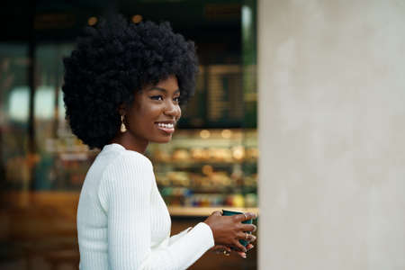 Portrait of young african woman with afro hairstyle smiling in urban backgroundの写真素材