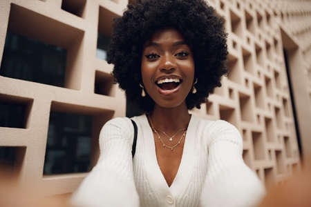 Stylish pretty african woman with Afro hairstyle posing near geometric wallの写真素材