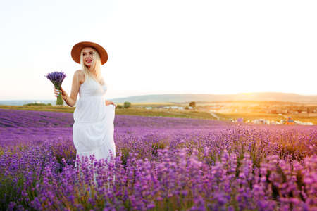 Young woman in long white dress standing in lavender fieldの写真素材