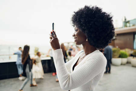 Beautiful young african woman using mobile phone in the streetの写真素材