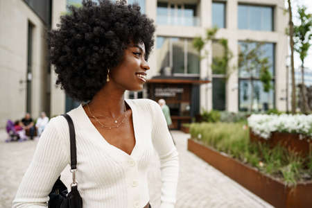 Portrait of young african woman with afro hairstyle smiling in urban backgroundの写真素材