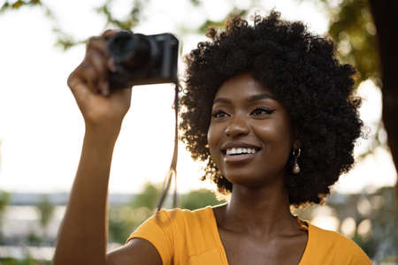 Smiling African american woman using professional camera at a streetの写真素材