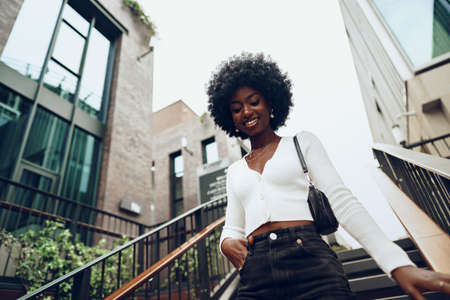 Young smiling african woman poses near stairs in the city
