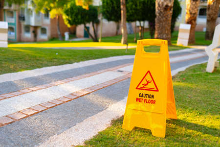Wet floor caution sign on hotel stone path