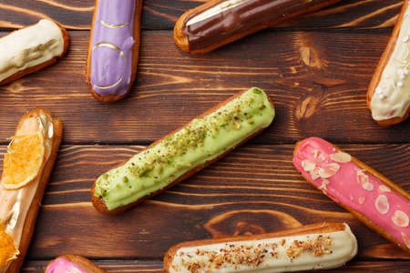 Assortment of sweet and colorful eclairs on wooden backgroundの写真素材