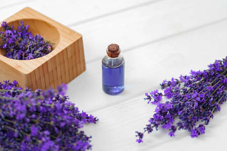 Herbal oil and lavender flowers on white wooden backgroundの写真素材