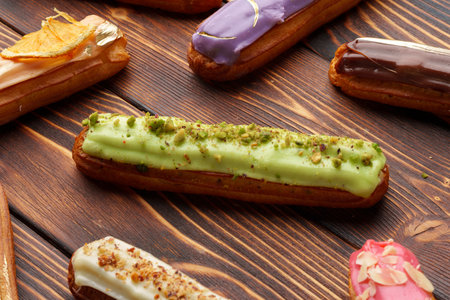 Assortment of sweet and colorful eclairs on wooden background