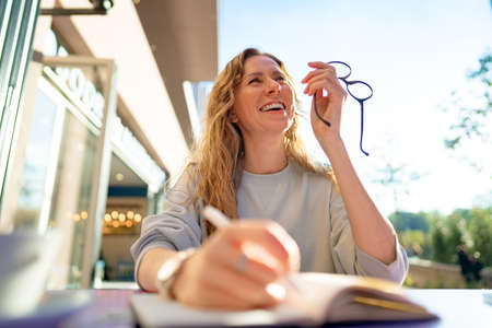 Casual woman sitting at table and taking notes in notebook .on the cafe terrace