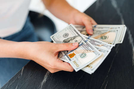 Close up of female hands counting dollar banknotes