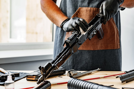 Close up of a man in apron wiping his firearm with a clothの写真素材