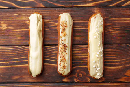 Eclairs with vanilla glaze on a wooden board