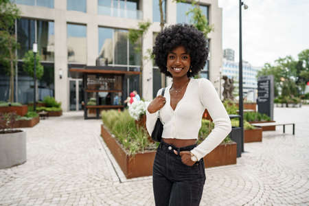 Portrait of young african woman with afro hairstyle smiling in urban backgroundの写真素材