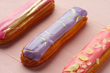 Eclair dessert with icing on pink wooden background