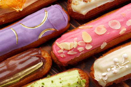 Assortment of sweet and colorful eclairs on wooden background