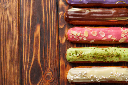 Assortment of sweet and colorful eclairs on wooden background