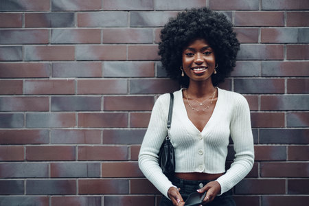 Beautiful young african woman using mobile phone in the street