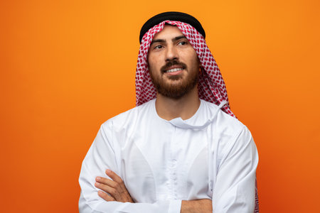 Portrait of young smiling Arab man on orange backgroundの写真素材