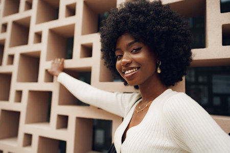 Stylish pretty african woman with hairstyle posing near geometric wallの写真素材