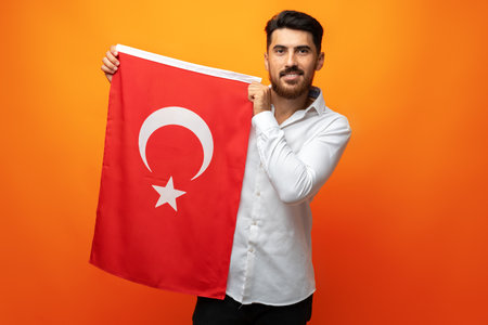 Young businessman holding a flag of Turkey on gray backgroundの写真素材