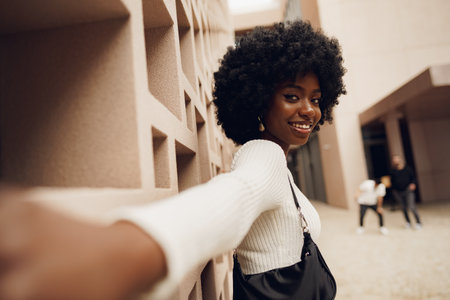 Stylish pretty african woman with Afro hairstyle posing near geometric wallの写真素材