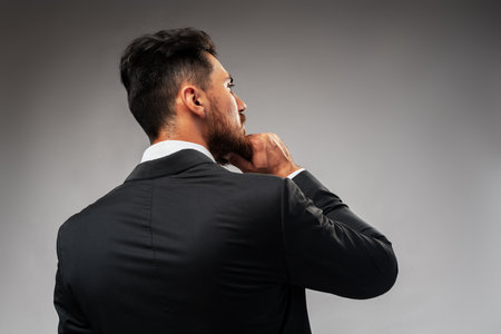 Studuo shot of thinking businessman standing over gray backgroundの写真素材