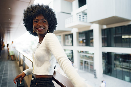 Portrait of young african woman with afro hairstyle standing at balcony and posing.の写真素材