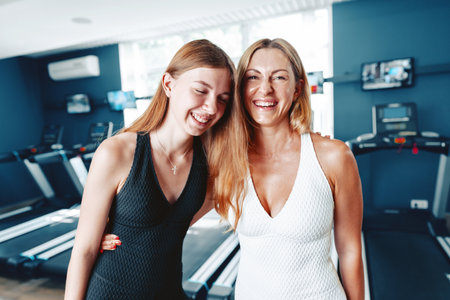 Portrait of a teen girl with her mother training together in a gymの写真素材