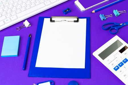 Composition of office lifestyle items on purple background, computer keyboard office supplies on desk in officeの写真素材