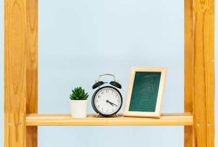 Wooden shelf with alarm clock and objects against blue backgroundの写真素材