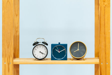Wooden shelf with alarm clock and objects against blue backgroundの写真素材