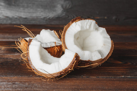 Broken coconut on a dark aged wooden table close up