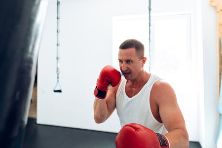 MIddle-aged boxer training in a gym, fighting with punching bag