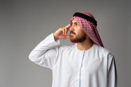 Young arab man wearing traditional clothes thinking about somethingの写真素材