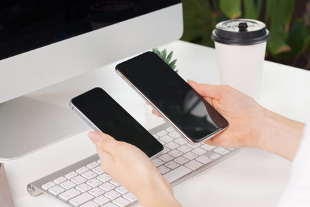 Close up of female hands using smartphone at office tableの写真素材