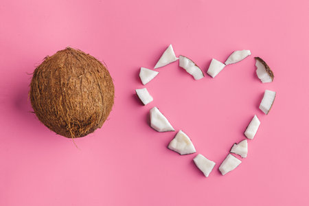 Broken coconut pieces on bright pink background, top view, copy space